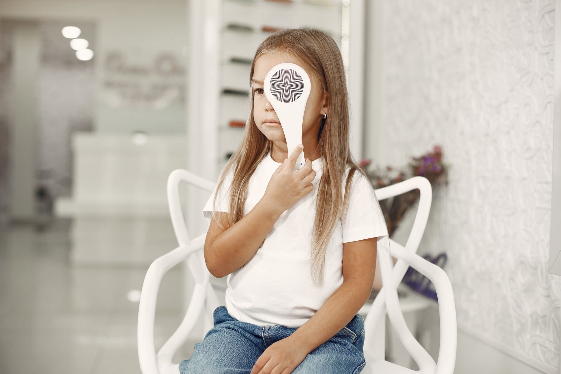 Child completing a monocular vision check with an eye occluder